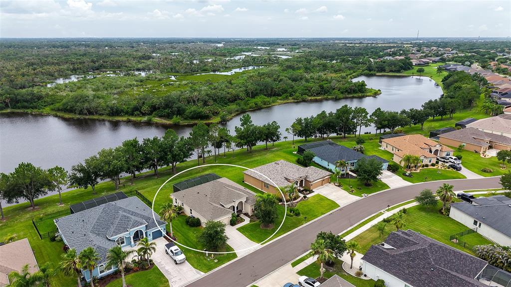 An aerial view of a single-story suburban house with a driveway and a backyard pond — 13515 22ND COURT E, PARRISH, FL
