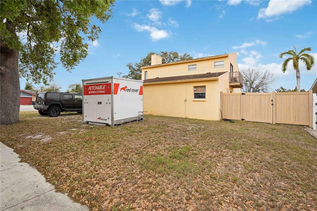 A yellow two-story house with a storage container and a black SUV in the yard — 6515 MAUNA LOA BOULEVARD, SARASOTA, FL