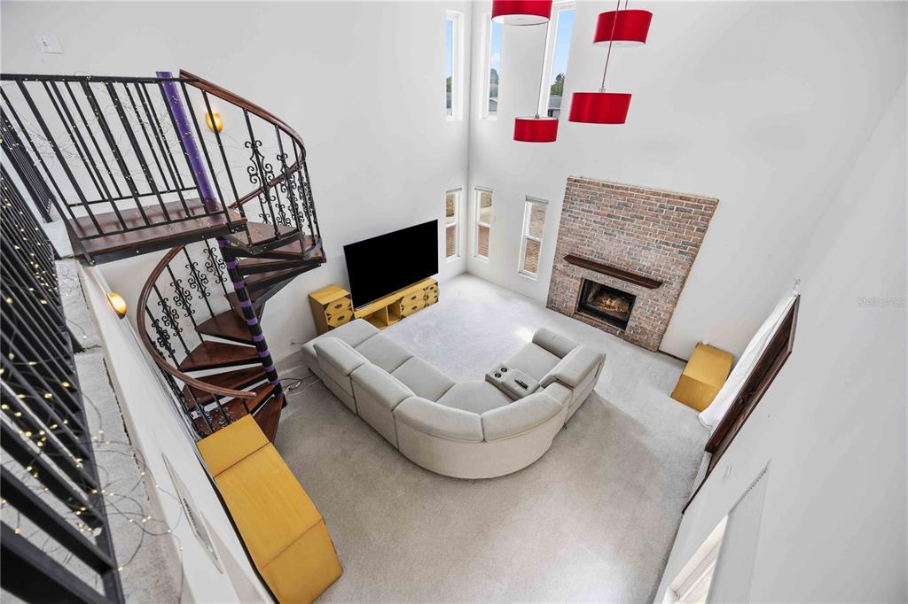 A high-angle view of a living room featuring a spiral staircase, fireplace, and sectional sofa — 6515 MAUNA LOA BOULEVARD, SARASOTA, FL