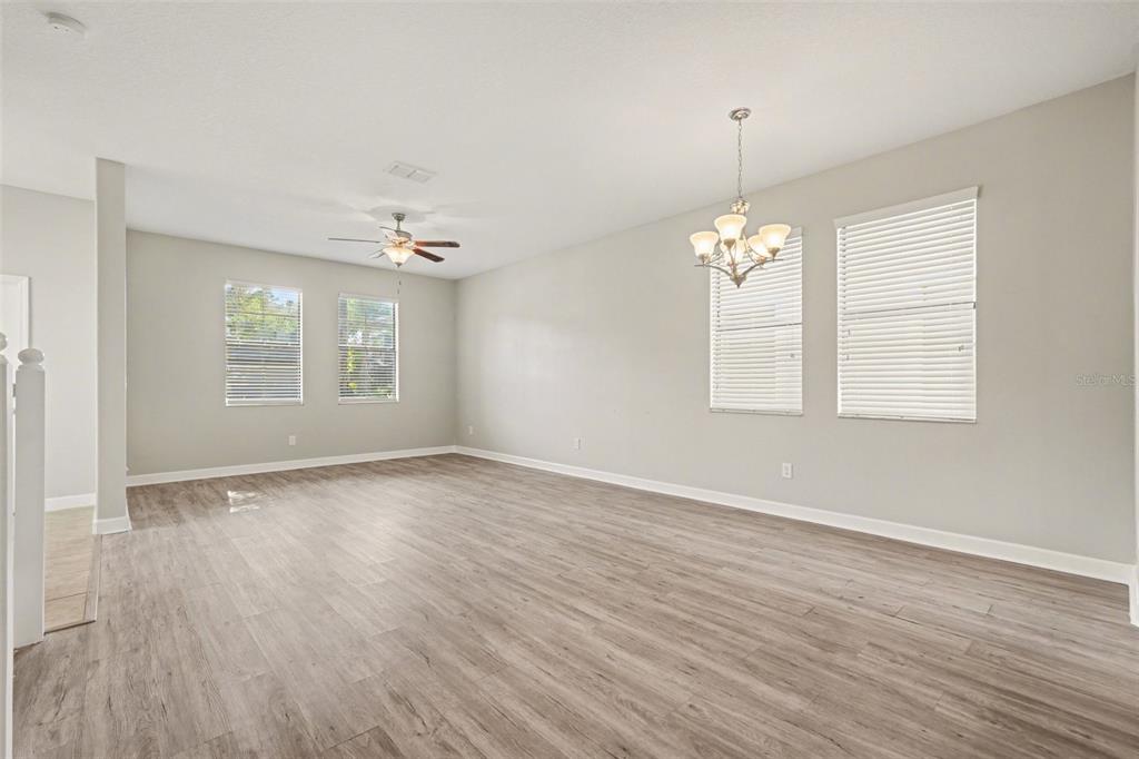 An empty room with light gray walls, wood-look flooring, a ceiling fan, and a chandelier — 28522 E PLEASANT BAY LOOP, WESLEY CHAPEL, FL
