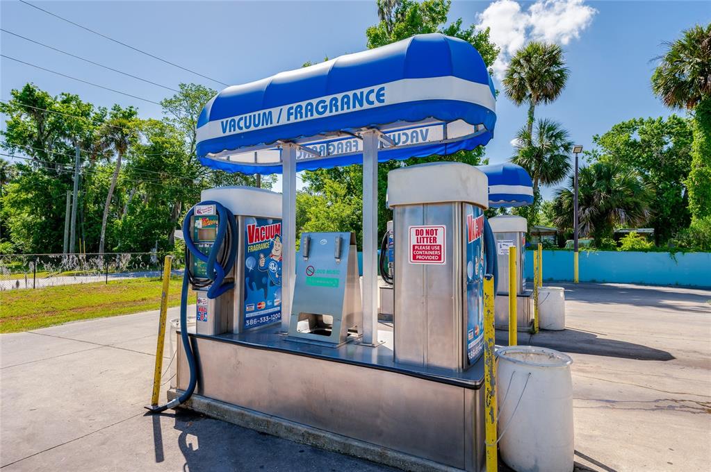 A blue and white canopy covers two stainless steel vacuum and fragrance stations outdoors — 1451 N NOVA ROAD, DAYTONA BEACH, FL