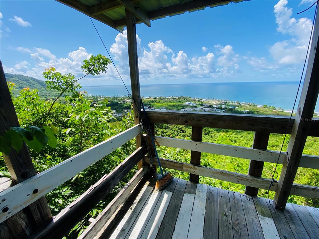 An elevated wooden deck overlooks a coastal landscape with a view of the ocean — FARM AMAZING OCEAN VIEW, PATILLAS, PR