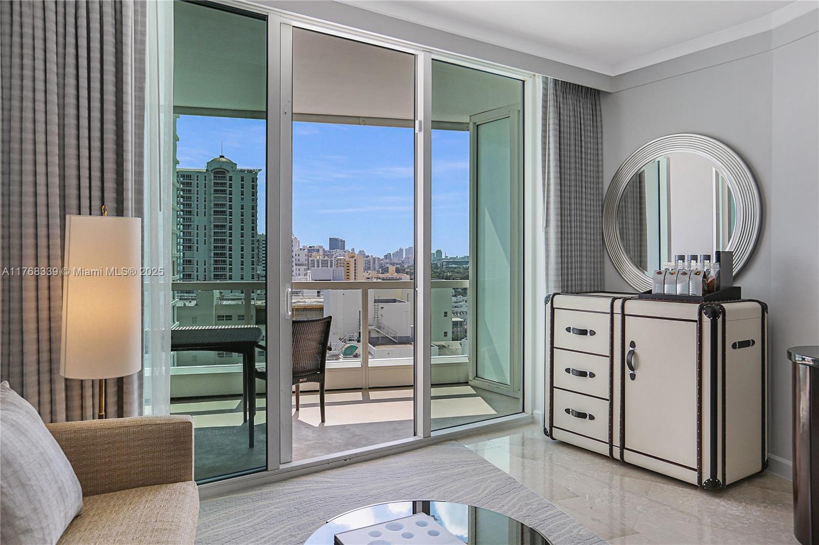 A hotel room features a balcony with city views, a dresser, and a round mirror — 4391 Collins Ave # 1415, Miami Beach FL 33140, MIAMI BEACH, FL