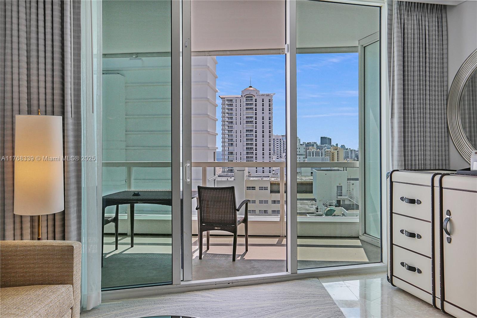 A bedroom with a balcony, sliding glass doors, a floor lamp, and a dresser — 4391 Collins Ave # 1415, Miami Beach FL 33140, MIAMI BEACH, FL