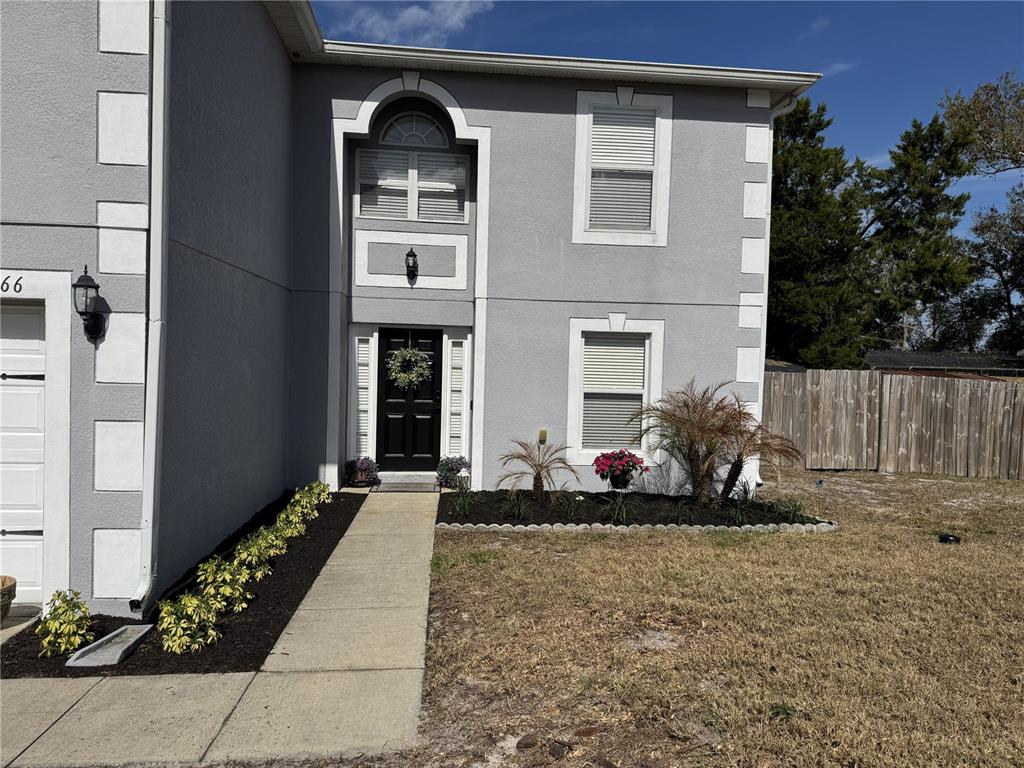 A two-story gray house features a black front door, white trim, and a concrete walkway — 1166 BALFOUR DRIVE, DELTONA, FL