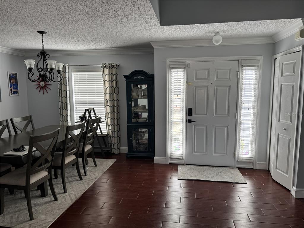 A dining area with a dark wood table and a front entryway with wood flooring — 1166 BALFOUR DRIVE, DELTONA, FL