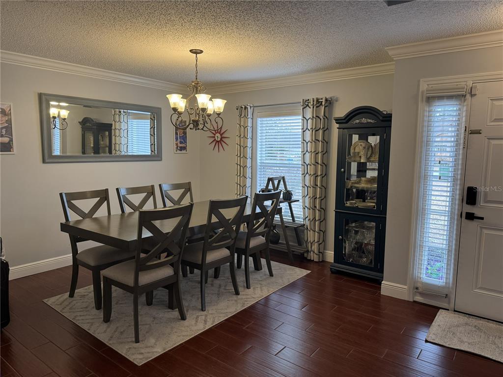 A dining room features a dark wood table, six chairs, a hutch, and hardwood floors — 1166 BALFOUR DRIVE, DELTONA, FL