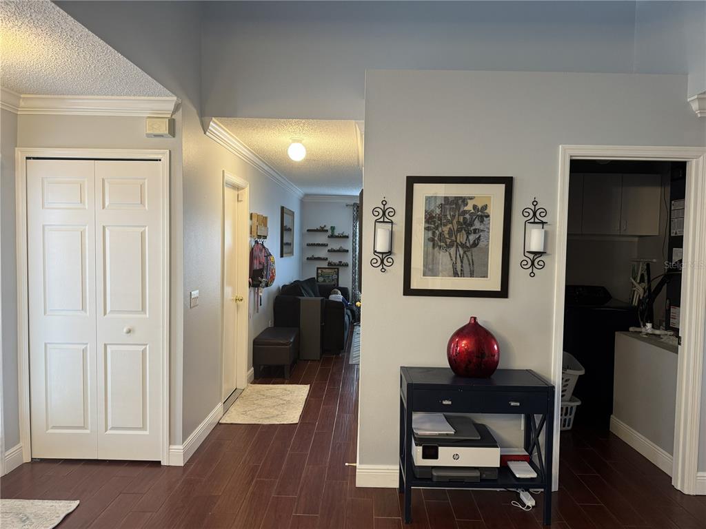 A hallway with dark wood-look flooring leads to a living area past a side table — 1166 BALFOUR DRIVE, DELTONA, FL