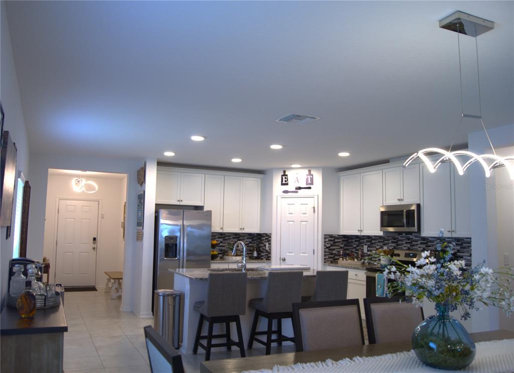 A kitchen with white cabinets, granite countertops, a center island, and a dining area — 12407 HILLTOP FARMS DRIVE, DADE CITY, FL