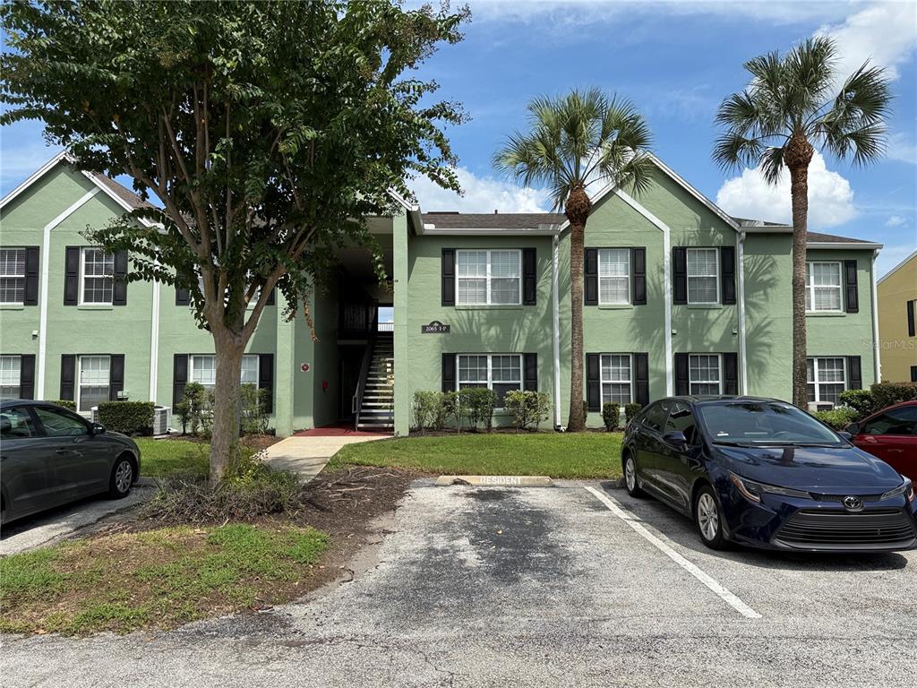 A three-story green apartment building features a central stairwell and parking spaces in front — 2065 DIXIE BELLE DRIVE UNIT 2065M, ORLANDO, FL