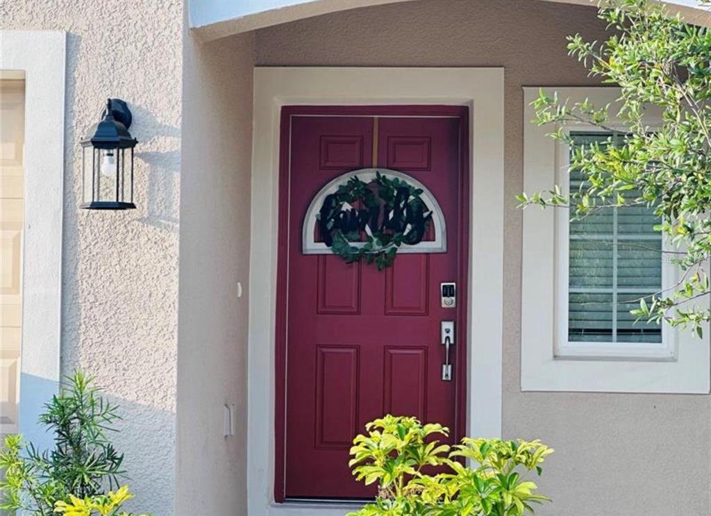 A red front door with a semi-circular window and wreath sits beside a wall lantern — 4512 TEOLI COURT, KISSIMMEE, FL