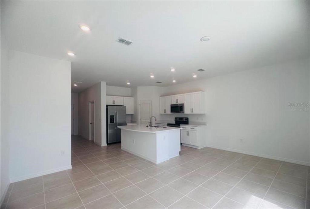A kitchen with white cabinets, stainless steel appliances, and a central island on tile flooring — 4512 TEOLI COURT, KISSIMMEE, FL
