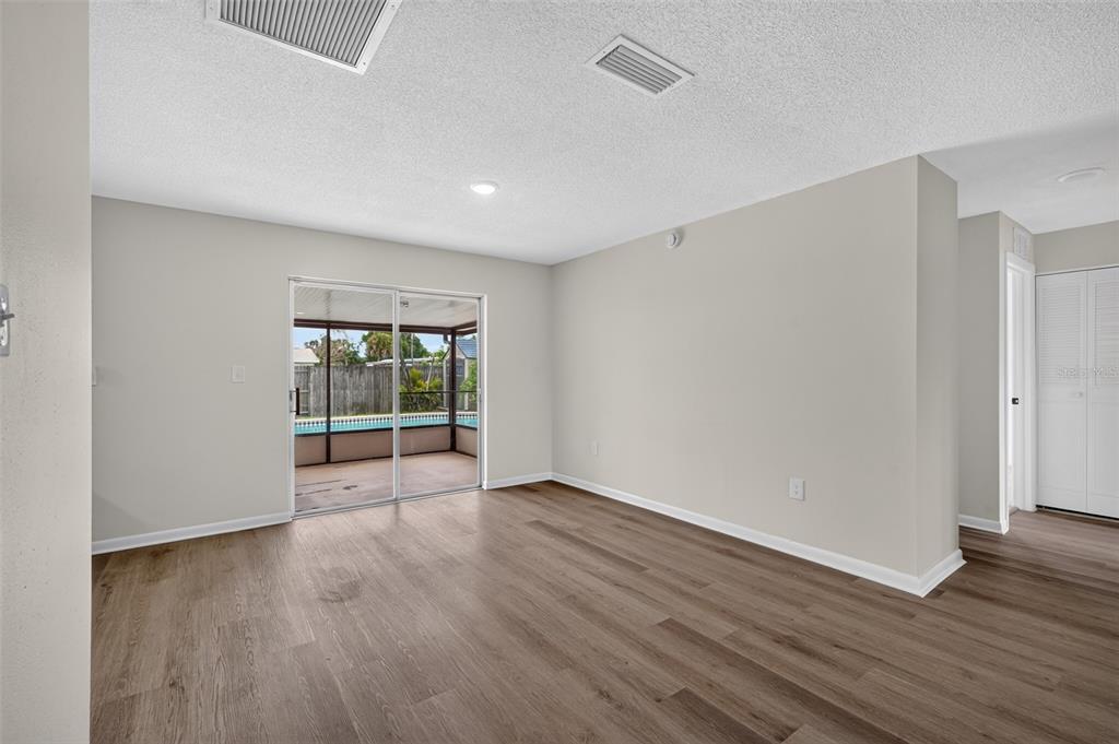 An empty room with wood-look flooring, light walls, and sliding glass doors leading to a patio — 5181 FREDERICK AVENUE, WEST MELBOURNE, FL