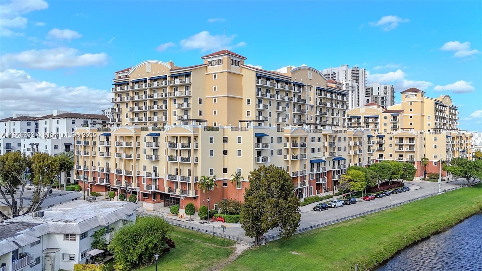 An aerial view shows a large, multi-story apartment complex with balconies next to a canal — 8395 SW 73rd Ave # 509, Miami FL 33143, MIAMI, FL
