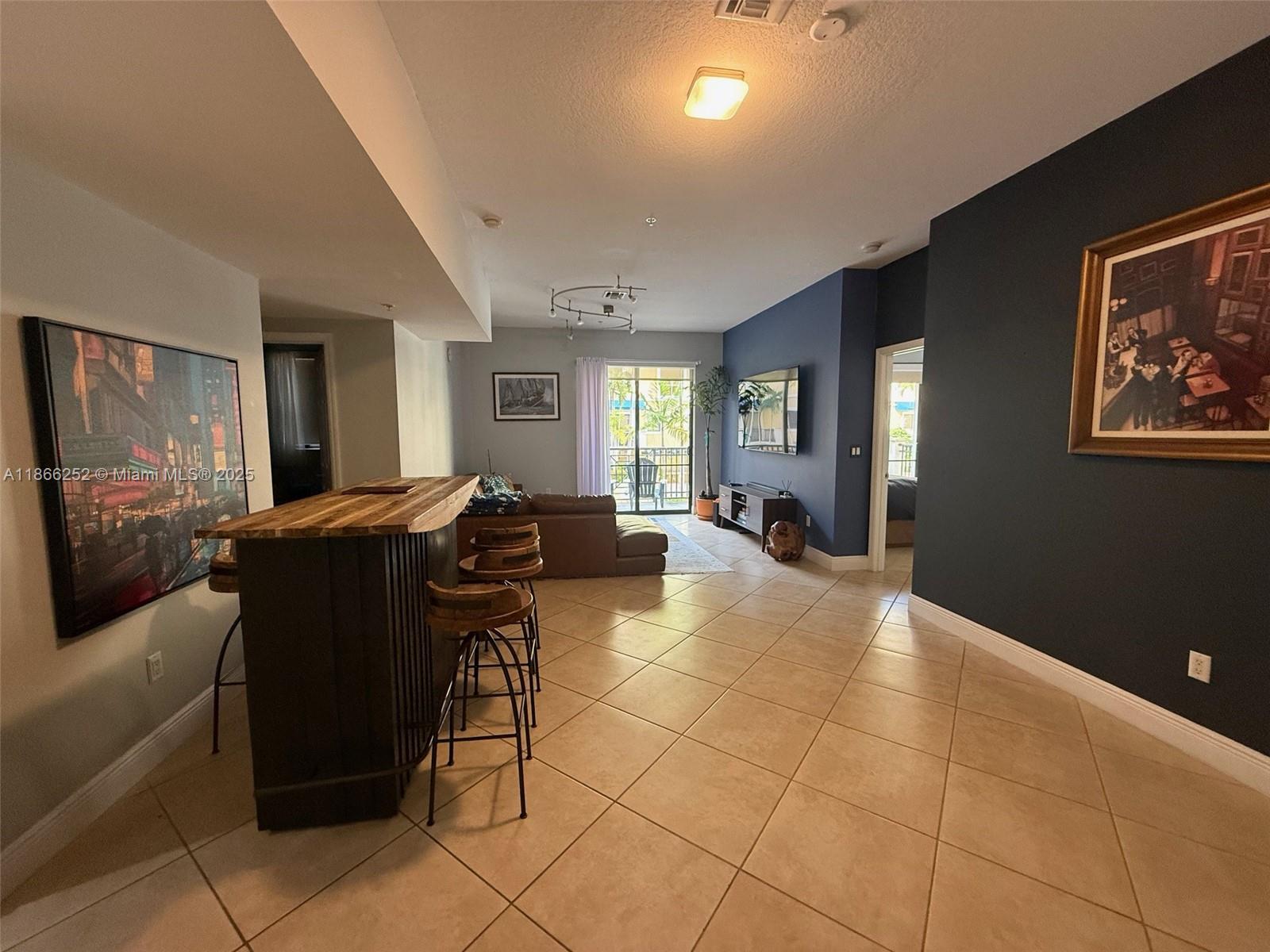 An open-concept living area features a wooden bar, tiled floors, and a dark accent wall — 8395 SW 73rd Ave # 509, Miami FL 33143, MIAMI, FL