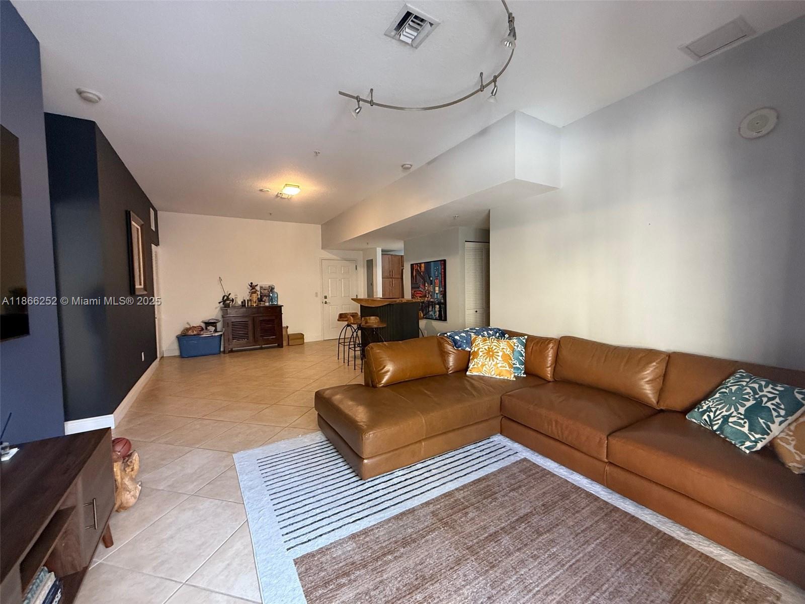 A living room features a brown leather sectional sofa, tile flooring, and a kitchen bar — 8395 SW 73rd Ave # 509, Miami FL 33143, MIAMI, FL