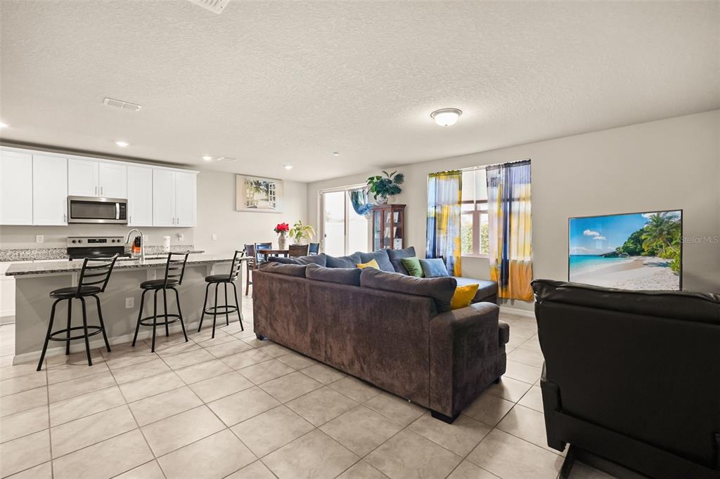 An open-concept kitchen and living area features white cabinets, a sectional sofa, and tile flooring — 1166 YUMURI STREET, WINTER HAVEN, FL