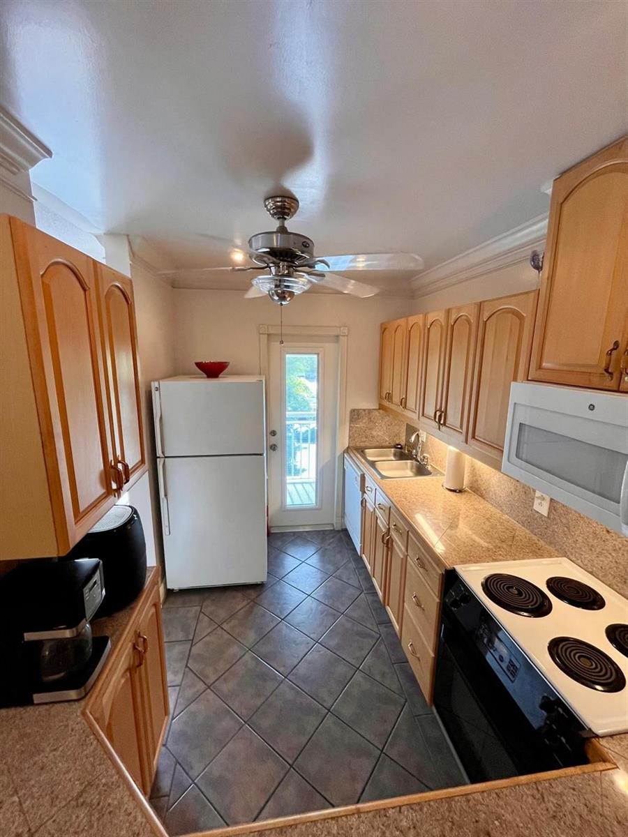 A galley kitchen features light wood cabinets, granite countertops, stainless steel appliances, and tile flooring — 1951 NE 39th Street # 361, Lighthouse Point FL 33064, LIGHTHOUSE POINT, FL