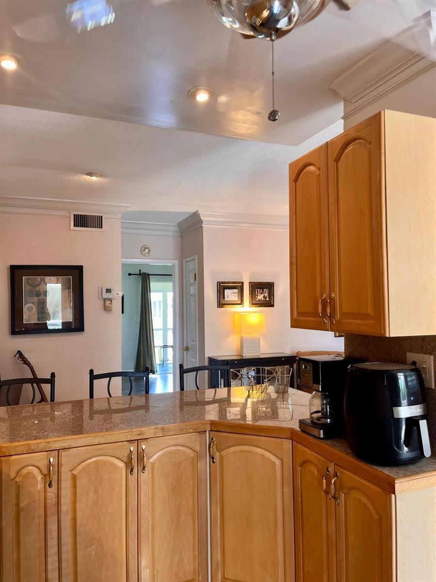 A kitchen with light wood cabinets, a granite countertop, and a view into a hallway — 1951 NE 39th Street # 361, Lighthouse Point FL 33064, LIGHTHOUSE POINT, FL