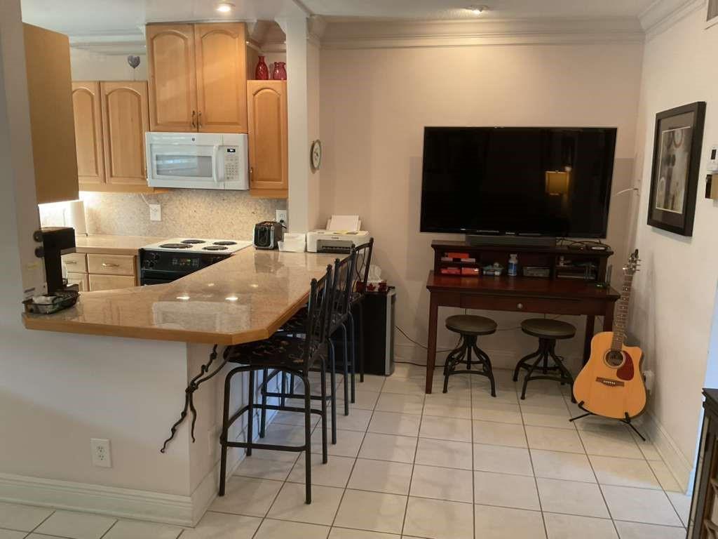 A kitchen with light wood cabinets and a granite breakfast bar next to a living area — 1951 NE 39th Street # 361, Lighthouse Point FL 33064, LIGHTHOUSE POINT, FL