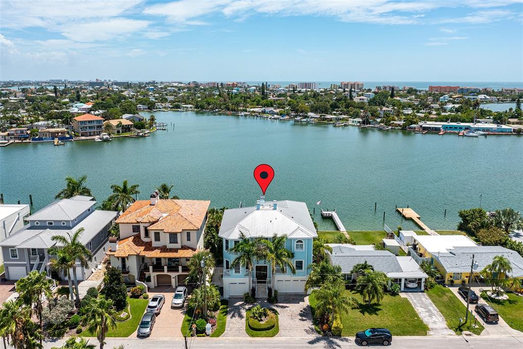 An aerial view shows a light blue waterfront house with a metal roof and dock — 821 BAY POINT DRIVE, MADEIRA BEACH, FL