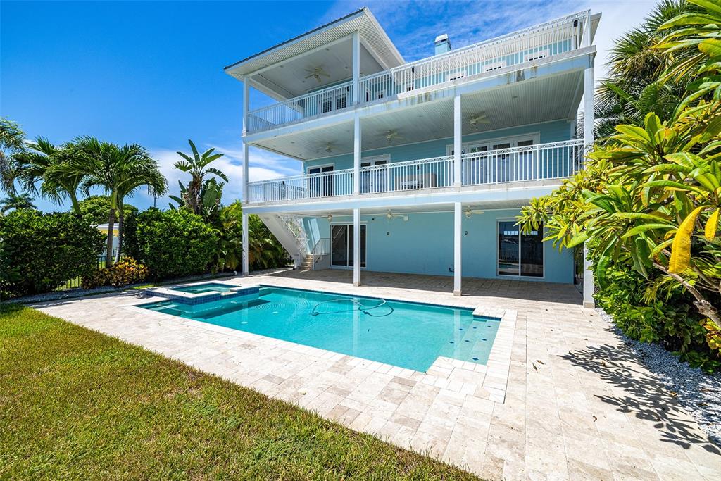 A three-story light blue house features multiple balconies, a swimming pool, and a patio — 821 BAY POINT DRIVE, MADEIRA BEACH, FL