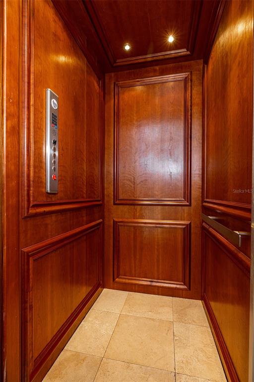 An elevator interior features wood-paneled walls, a metal control panel, and light-colored tile flooring — 821 BAY POINT DRIVE, MADEIRA BEACH, FL