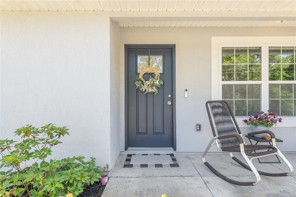 A front entryway features a dark blue door, a rocking chair, and a small plant — 20264 SW 69TH PLACE, DUNNELLON, FL