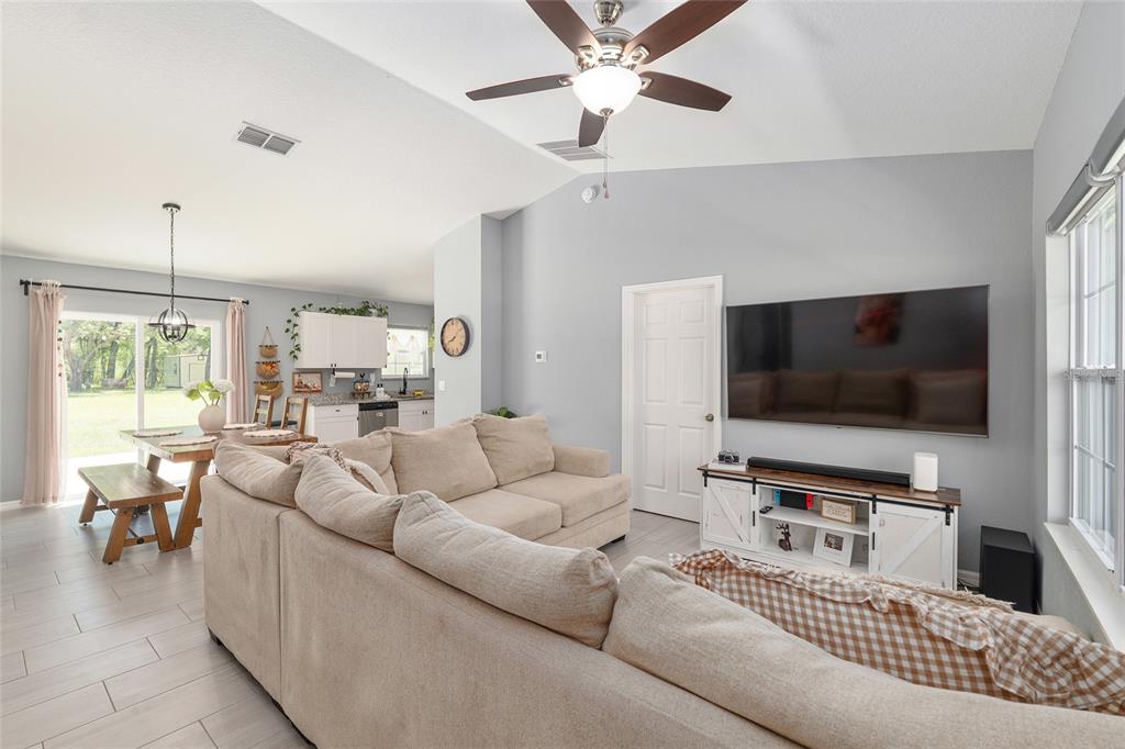 A living room with a sectional sofa, a wall-mounted television, and an adjacent dining area — 20264 SW 69TH PLACE, DUNNELLON, FL
