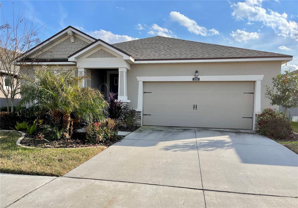 A single-story suburban house features a beige stucco exterior, a two-car garage, and landscaping — 13205 ORCA SOUND DRIVE, RIVERVIEW, FL