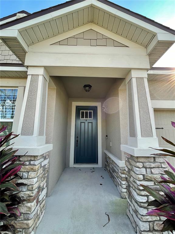 The exterior view shows a covered entryway with stone-based pillars and a dark front door — 13205 ORCA SOUND DRIVE, RIVERVIEW, FL