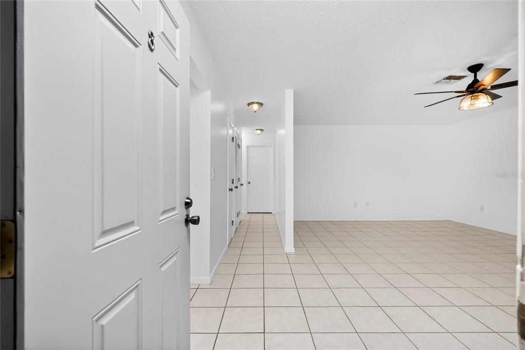 An interior view shows a tiled entryway leading to a living area with a ceiling fan — 1217 AQUI ESTA DRIVE UNIT 8, PUNTA GORDA, FL
