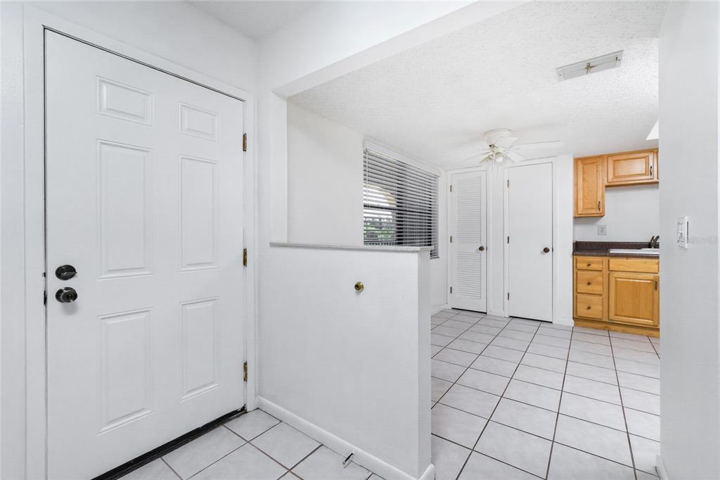 An entryway with white tile floors leads into a kitchen area with light wood cabinets — 1217 AQUI ESTA DRIVE UNIT 8, PUNTA GORDA, FL