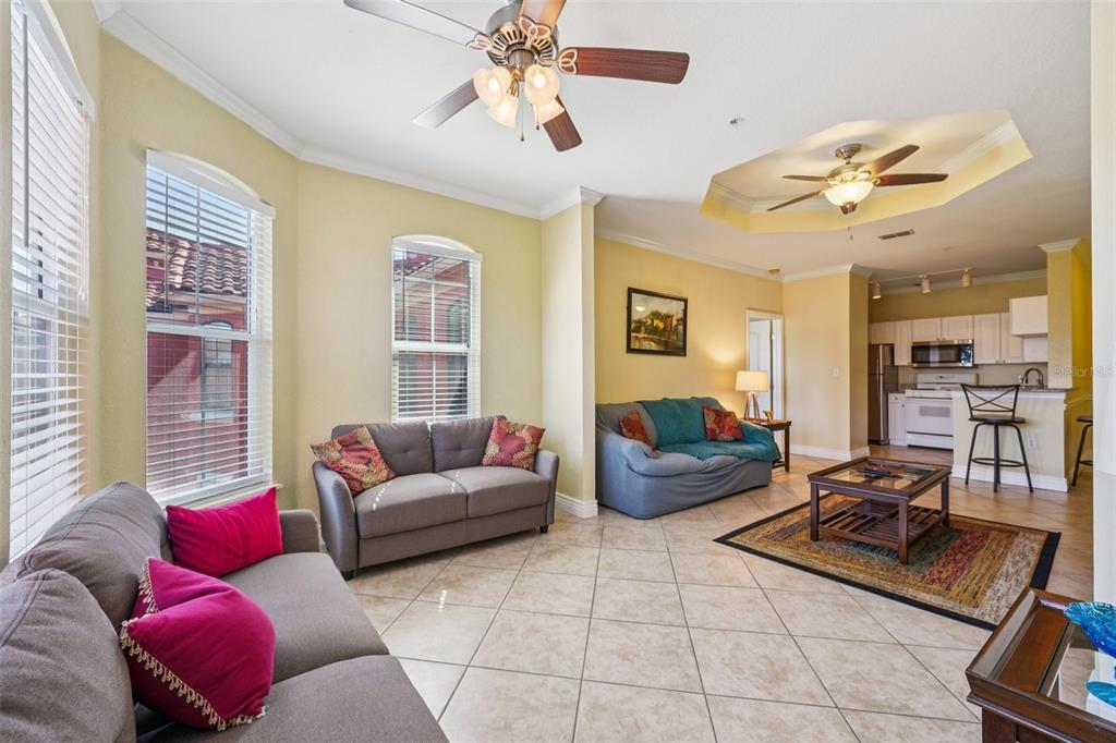 A living room with tile floors, two sofas, a coffee table, and an open kitchen — 2713 VIA MURANO UNIT 233, CLEARWATER, FL