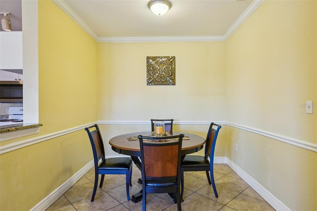 A dining area with a round wooden table, four chairs, and yellow walls — 2713 VIA MURANO UNIT 233, CLEARWATER, FL