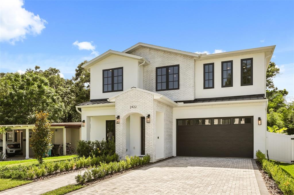 A two-story house with white brick accents, black window frames, and a paved driveway — 2422 MUSSELWHITE AVENUE, ORLANDO, FL