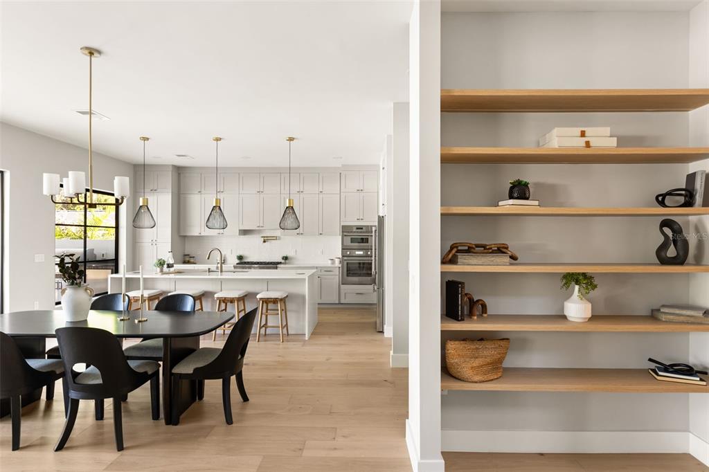 A modern kitchen and dining area feature light wood floors, white cabinetry, and open shelving — 2422 MUSSELWHITE AVENUE, ORLANDO, FL