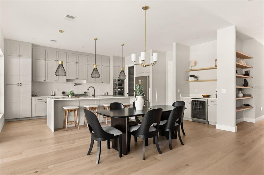A modern kitchen and dining area features light gray cabinetry, a central island, and wood flooring — 2422 MUSSELWHITE AVENUE, ORLANDO, FL