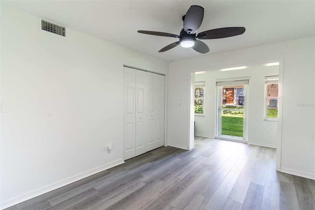 A room with white walls, gray wood-look flooring, a ceiling fan, and a glass door — 1100 MARTINIQUE DRIVE UNIT 106, WINTER HAVEN, FL