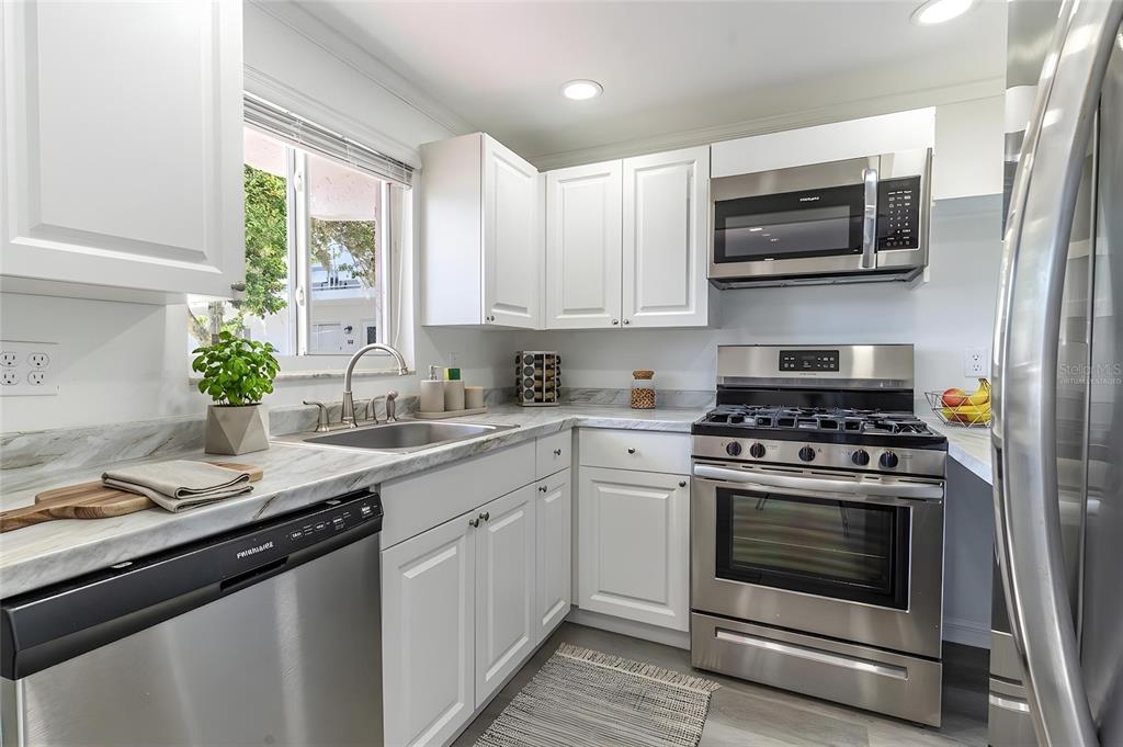 A kitchen with white cabinets, stainless steel appliances, and marble-look countertops — 1100 MARTINIQUE DRIVE UNIT 106, WINTER HAVEN, FL