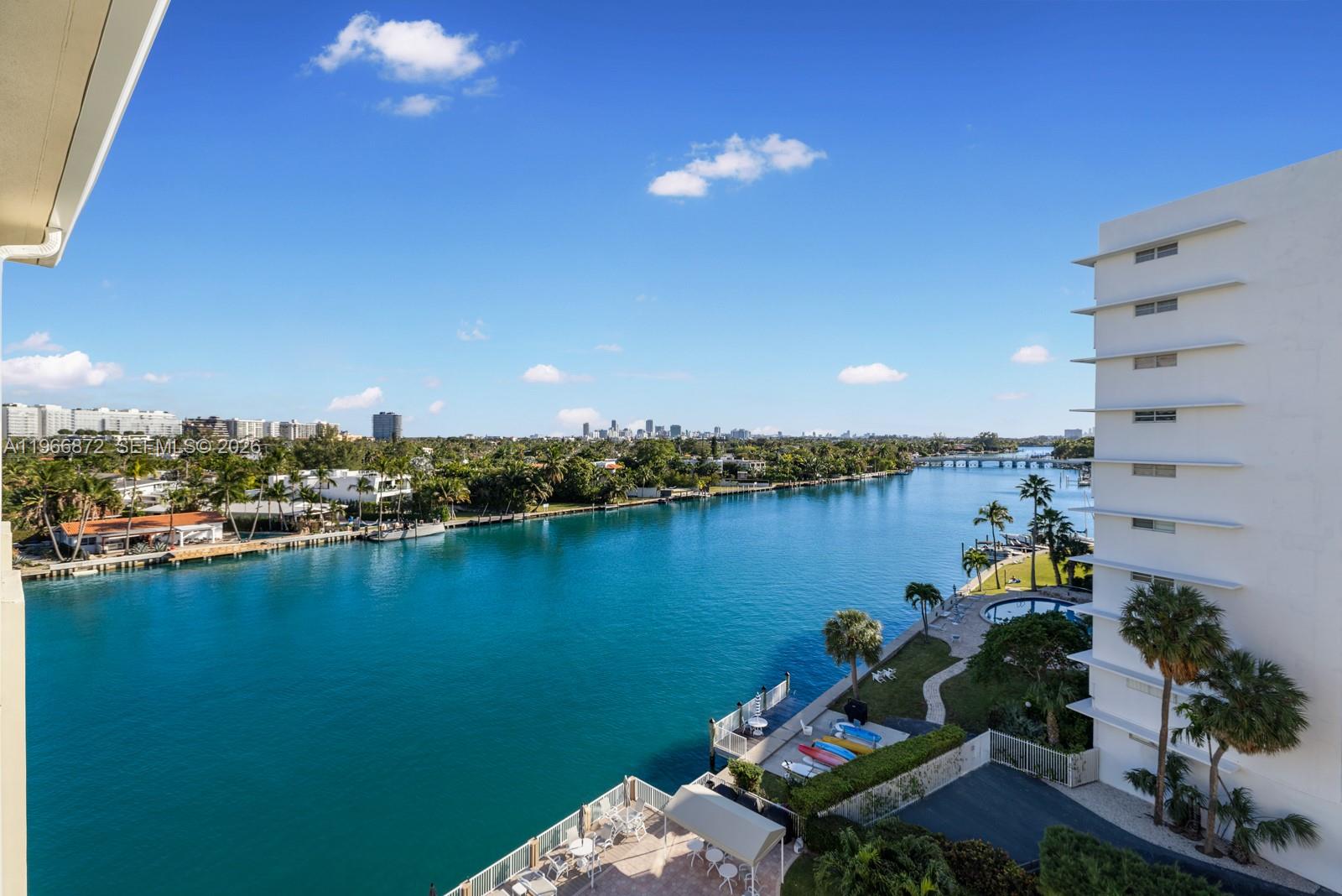 A high-angle view shows a blue waterway bordered by palm trees, residential buildings, and a pool — 9111 E Bay Harbor Dr # D, Bay Harbor Islands FL 33154, BAY HARBOR ISLANDS, FL