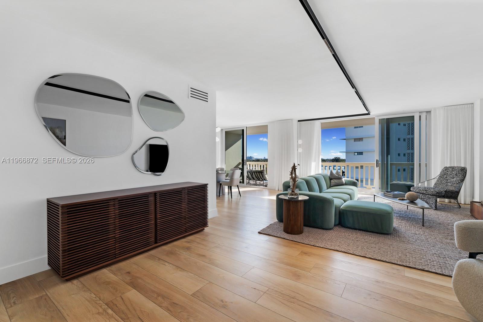 A living room features a wooden console, three organic-shaped mirrors, and a green sofa — 9111 E Bay Harbor Dr # D, Bay Harbor Islands FL 33154, BAY HARBOR ISLANDS, FL