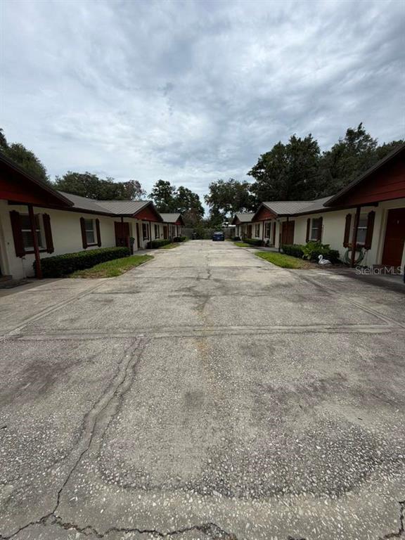 A paved driveway leads between two rows of single-story apartment buildings with red trim — 2366 LAKE DRIVE NW, WINTER HAVEN, FL