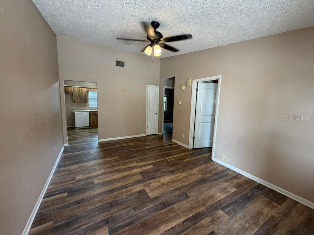 An empty room with wood-look flooring, a ceiling fan, and doorways leading to other rooms — 2366 LAKE DRIVE NW, WINTER HAVEN, FL