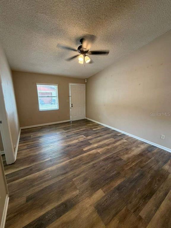 An empty room features wood-look flooring, a ceiling fan, and a white door — 2366 LAKE DRIVE NW, WINTER HAVEN, FL