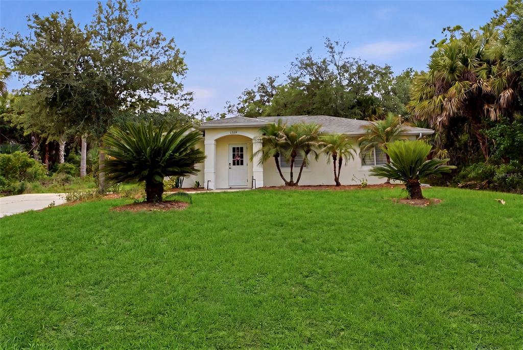 A single-story house with a white exterior, palm trees, and a green lawn — 1709 KERMAN STREET, NORTH PORT, FL