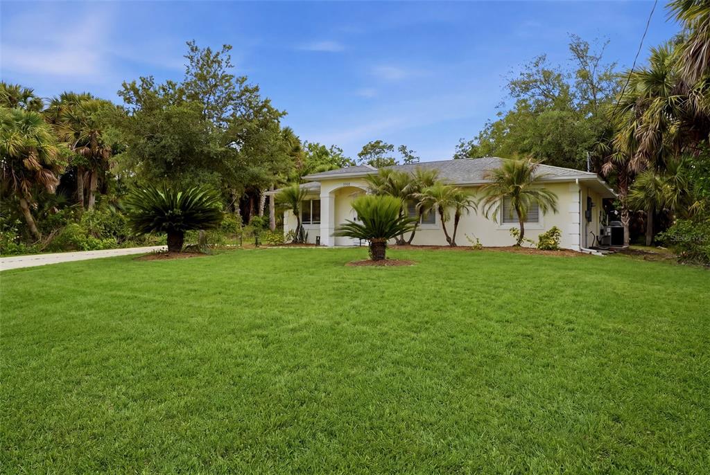 A single-story house with a light-colored exterior sits behind a large, grassy front lawn — 1709 KERMAN STREET, NORTH PORT, FL