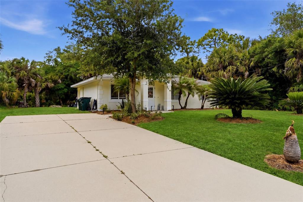 A single-story house with a concrete driveway, green lawn, and surrounding palm trees — 1709 KERMAN STREET, NORTH PORT, FL