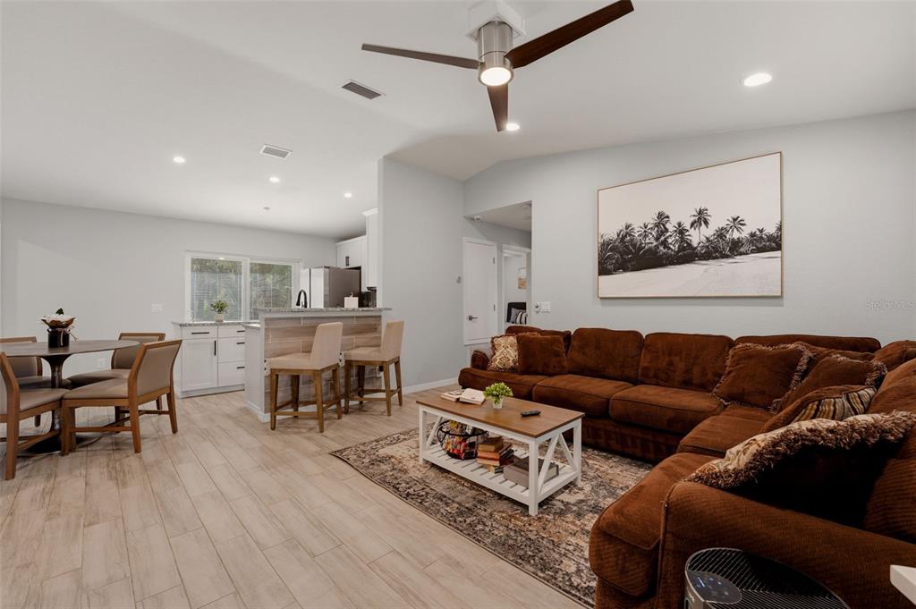 An open-concept living room and kitchen featuring a brown sectional sofa and dining area — 1709 KERMAN STREET, NORTH PORT, FL