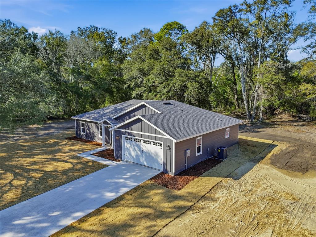 An aerial view of a gray single-story house with a two-car garage and wooded surroundings — TBD SW 170TH STREET, ARCHER, FL